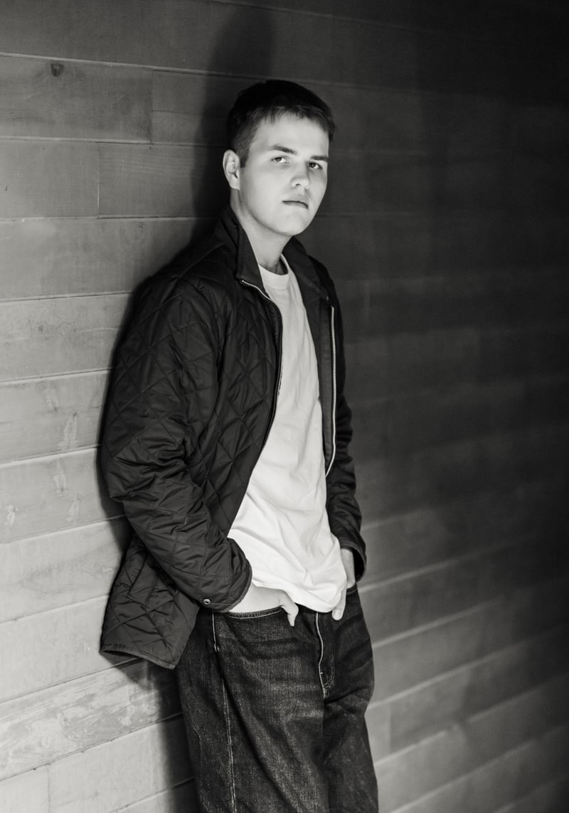 Logan leaning against a wall, hands in pockets